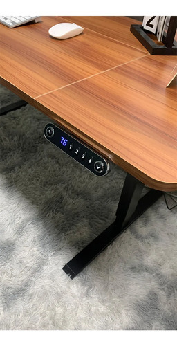 Escritorio eléctrico motorizado marrón en posición elevada con panel de control digital azul y base negra.