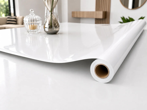 Rollo de papel autoadhesivo blanco liso sobre superficie, mostrando textura y formato de aplicación.